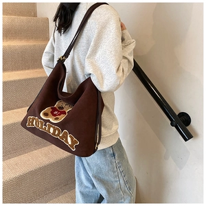 Detail of dark brown suede tote bag with teddy bear patch and holiday embroidery