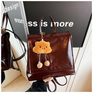 Detail of burgundy glossy PU leather backpack with a cute plush cloud charm