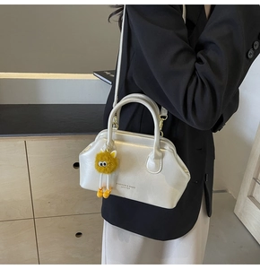 Dettaglio borsa a mano bianco perla con hardware dorato e charm in peluche giallo