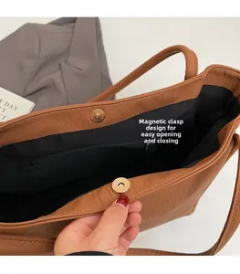Detail view of the brown leather tote bag featuring a magnetic closure and inner pocket