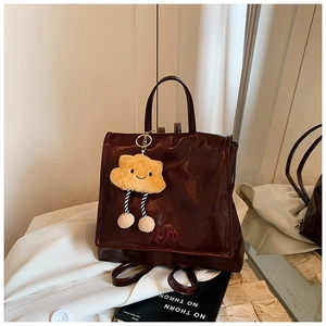 Detailed view of coffee brown leather backpack with plush cloud charm and vbm embroidery