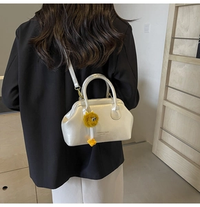 Dettaglio della borsa medica in pelle bianca con manico e ciondolo a forma di peluche giallo