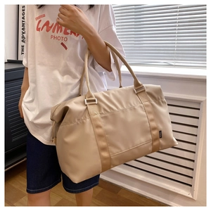 Detail of a beige waterproof nylon travel bag with wide handles in a modern home setting