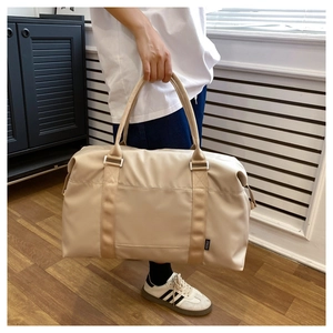 Detailed view of beige waterproof travel bag with sturdy handles and metal buckles