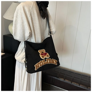 Detail of black canvas tote bag with plush teddy bear applique and Holiday relief text