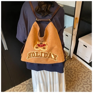 Brown canvas tote bag with holiday bear embroidery shown on shoulder of a model