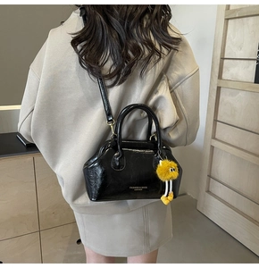 Dettaglio della borsa a tracolla in pelle verniciata nera con charm mostro in peluche