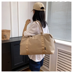 Detailed view of a large khaki waterproof travel bag shown carried by a model