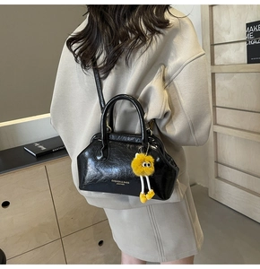 Dettaglio borsa in pelle nera lucida con ciondolo a forma di mostro di peluche giallo