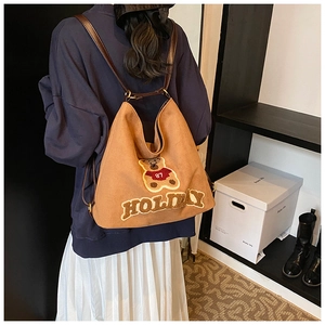 Detailed view of canvas tote bag featuring teddy bear patch and holiday lettering