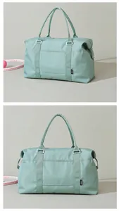Detail view of mint green waterproof travel bag with reinforced handles and brand logo