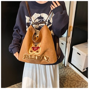 Detail of a brown suede tote bag with 3D teddy bear embroidery and HOLIDAY text