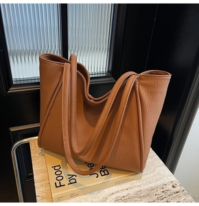 Close-up of caramel pebbled leather tote bag resting on books for a stylish look