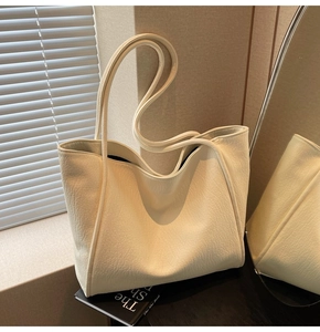 Detail of minimalist beige tote bag with litchi texture on black books in soft light