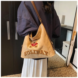 Detail of khaki suede tote bag with teddy bear embroidery and brown leather strap