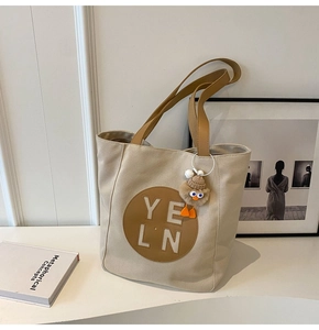 Detail of canvas tote bag with leather logo patch and cute plush duck charm