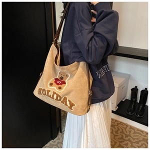 Detail of khaki tote bag with plush teddy bear patch and holiday letter embroidery