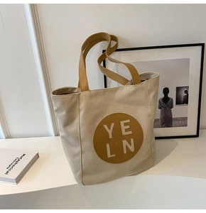 Detail view of large canvas tote bag with brown handles and central YELN logo detail