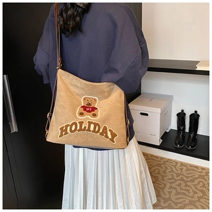 Detail of canvas tote bag featuring bear embroidery and adjustable brown shoulder strap