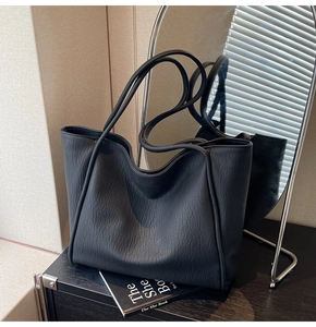 Close-up of black pebble leather tote bag with elegant minimalist shoulder straps