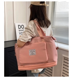 Pink travel bag detail featuring front square pocket and expanded zipper bottom layer