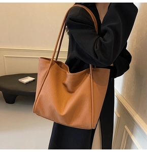 Caramel brown leather tote bag with lychee texture shown on model side profile