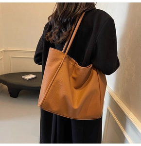 Close-up of caramel brown tote bag showing textured faux leather and slim shoulder straps