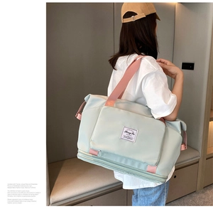 Large capacity mint green travel duffel bag with pink straps worn by female model