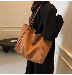 Detail of caramel textured leather tote bag showing spacious design and strap on model