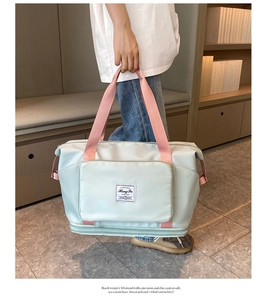 Detail of mint green travel bag with pink handles and expandable bottom zipper
