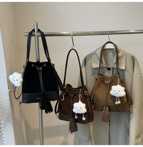 Detail of vintage suede bucket bags with tassels and plush cloud charms on a rack