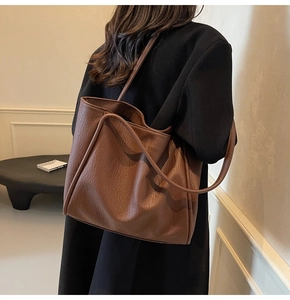 Macro detail of deep brown faux leather tote with textured lychee grain and slim straps