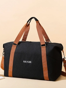 Large black canvas travel bag with tan straps and shoulder strap for gym and yoga