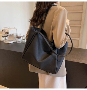 Close-up of black lychee grain leather tote bag worn with a khaki blazer for style