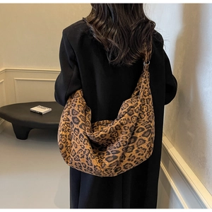 Detailed back view of a large leopard print crescent bag on a model in a minimalist room