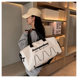 Close-up of a white waterproof sports tote bag worn by a model in a cozy indoor setting