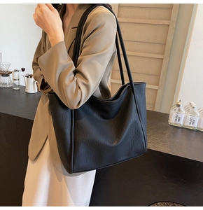Detailed close-up of textured black leather tote bag with elegant vertical stitching details