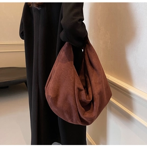 Suede-textured dark red hobo shoulder bag worn over a classic black coat in style