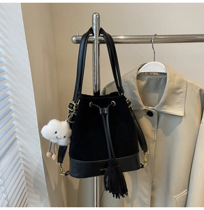 Detail of black drawstring bucket bag featuring tassels and a white plush cloud charm