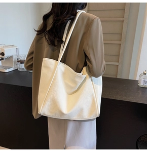 Close-up of a white tote bag with lychee texture and stitching detail on a shoulder strap