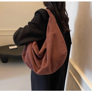 Brown large suede hobo bag on shoulder, showing slouchy texture and minimalist style
