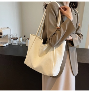 Detailed view of large cream tote bag with soft pleated texture and shoulder strap