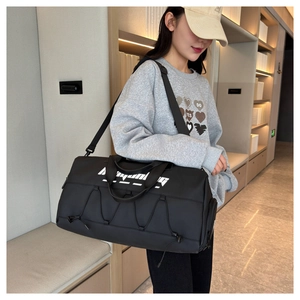 Detailed view of black waterproof sports tote bag with white lettering and adjustable strap