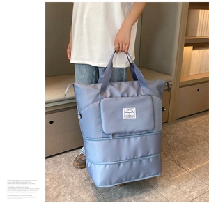Large capacity blue travel tote bag held by a person in a minimalist interior
