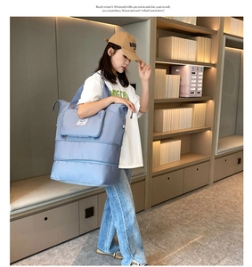 Close-up of light blue folding travel bag with dual zipper expansion layers for extra space