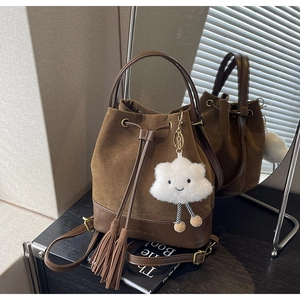 Detail of dark brown suede bucket bag featuring long tassels and a cute white cloud charm
