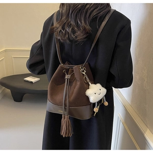 Detail of dark brown suede bucket bag with long tassels and plush star smiley pendant