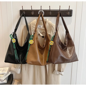 Detail of large tote bags in three colors featuring green rope knot and smiley charm