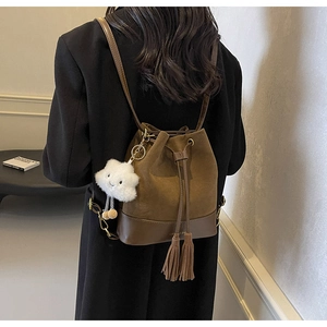Brown bucket bag on model featuring drawstring closure and white cloud charm detail