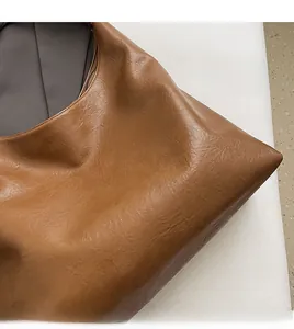 Detailed macro view of caramel brown faux leather texture on minimalist tote bag